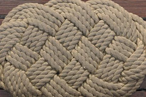 Braided rope pattern on wooden deck showcasing nautical craftsmanship Foto stock