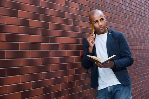Brain development. Young guy standing on wall reading book touching head with Foto stock