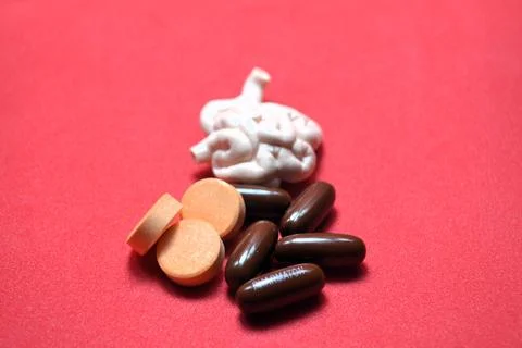 Brain model with orange tablets and brown capsules on red surface showcasin.. Foto stock