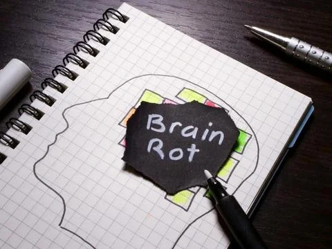 Brain rot note over a head drawing in notebook highlights digital overload. Foto stock