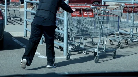 BRAINERD, MN - 29 MAR 2019: Woman rolls shopping cart into parking lot corral. Stock Footage 106789603