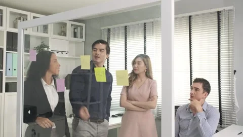 Brainstorming young business teamwork using post it puts ideas on glass boards. Stock Footage 247350195