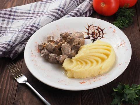 Braised beef in sauce and mashed potatoes on a white plate Stock Photos