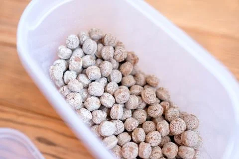 Bran in a plastic container. Dry edible balls. Wood background Foto stock