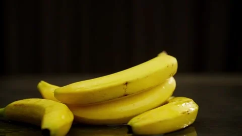 A branch of three bananas falls on the table, forming a spray of water. Stock Footage 269929960