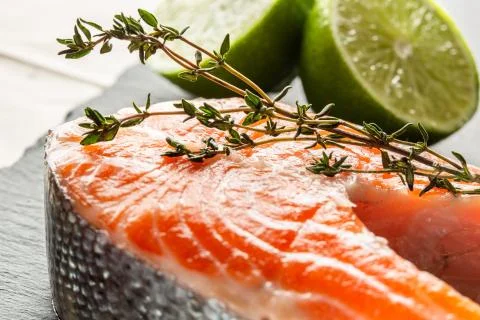 Branch of thyme lying on the smooth red fish surface Stock Photos