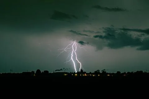 Branched lightning strike over distant horizon during night thunderstorm Fotos Stock