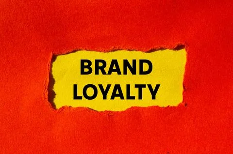 Brand loyalty message written on ripped torn red paper on yellow background.. Stock Photos