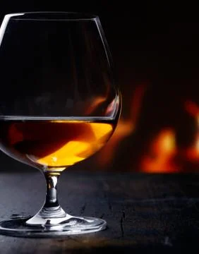 Brandy snifter warming before a glowing fire Stock Photos
