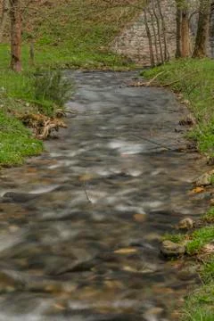 Branna river in spring cloudy evening with fresh green grass and railway viad Stock Photos