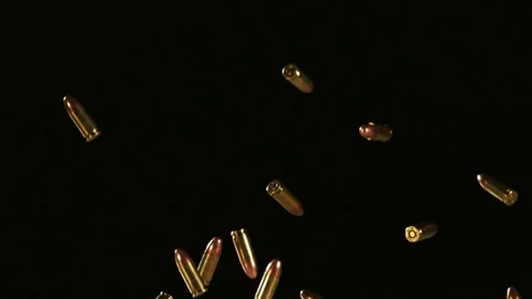 Brass bullet casings fall through dark air Stock Footage 327178168
