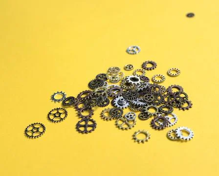 Brass cog wheels of different sizes lying on yellow Stock Photos