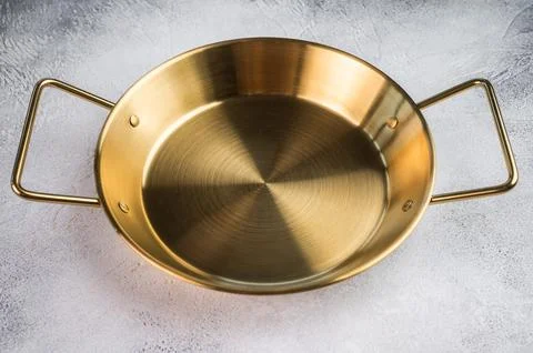 Brass colored cooking pan on dramatic grey backdrop, flat lay kitchen equip.. Stock Photos