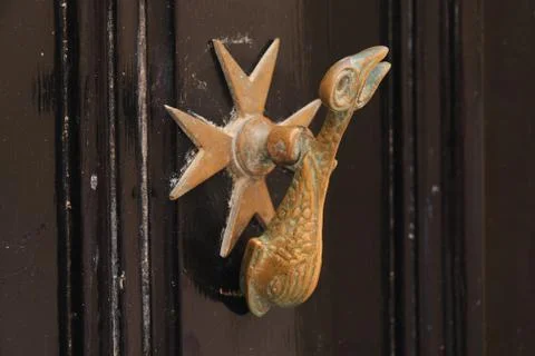 Brass door knocker shape of dolphin on old brown doors Stock Photos