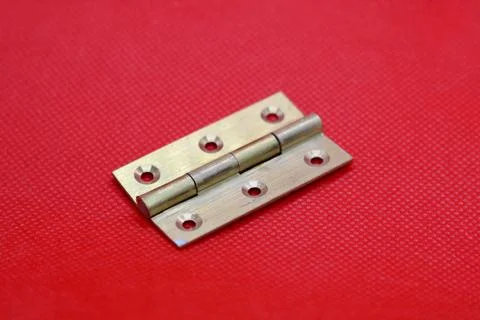 Brass hinge without screws against plain red background with copyspace Stock Photos