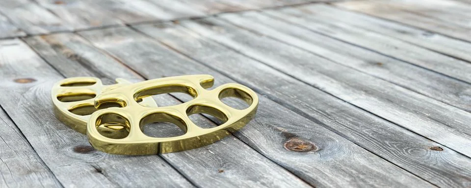 Brass knuckle-duster, weapon for hand on wooden table 3d render illustration Illustrazione stock