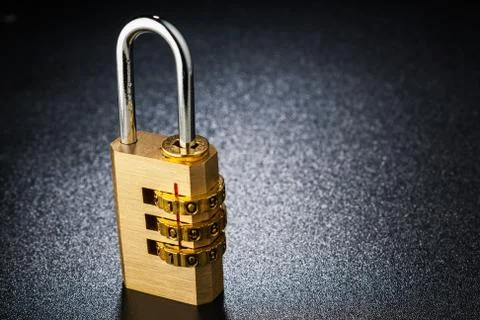 Brass lock with the code set on the dark surface. Texture background. Stock Photos
