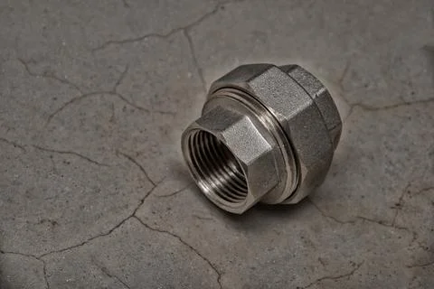 Brass reducing coupling. Female threaded pipe fitting on dark gray cement bac Stock Photos