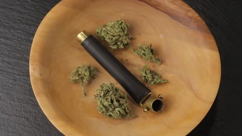 Brass smoking pipe with multiple sativa and indica weed buds in wooden plate on Vidéo 121568746