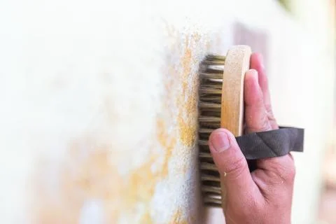 Brass wire brush cleaning surface of wall Stock-Fotos