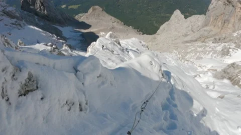 Brave climber climbing mountain using rope in the snow - via ferrata scary view Video stock 161596270