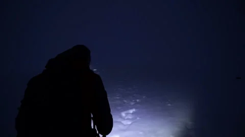 Brave explorer with headlamp commits a night climb in snowy mountain Stock Footage