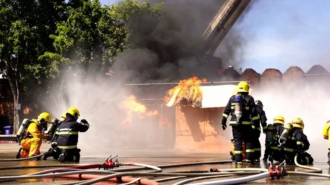 Brave firefighter using extinguisher and water from hose for fire fighting Stock Footage 120156396