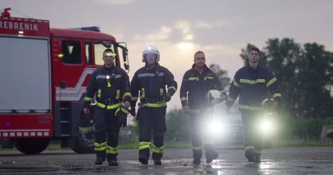 Brave Firefighters Team Walking to the Camera. In Background Paramedics and Stock Footage 283098119