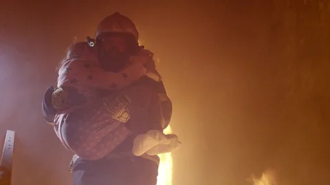 Brave Fireman Descends Stairs of a Burning Building with a Saved Girl in His Arm Stock Footage 71106733