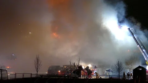 Brave firemen tackle large fire on windy night exposing to danger Video stock 129649871