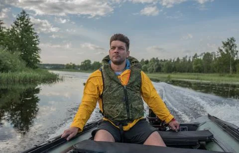 Brave handsome man is operating of boat on the river Stockfoto's