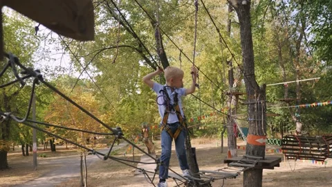 Brave little boy passing the cable route high among trees. Stock Footage 155993728