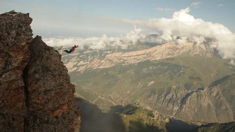 Brave man jumping off a cliff, rope jumping in the mountains. Stock Footage 97766195