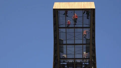 Brave people tourists walk on transparent floor high in sky on observation place Stock Footage