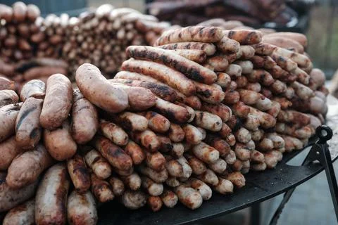 Bravurst on a large round grill, selective focus. Lots of sausages on grill. Stock Photos