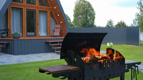 Brazier with burning wood on the background of a modern triangular house Stock Footage 281101082