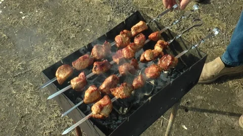 Brazier with a shish kebab on the earth, a man turns skewers. Stock Footage 68341745