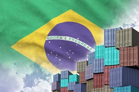 Brazil flag and big stack of shipping cargo containers in docks with sky Stock Photos