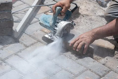 Brazilian construction worker using a concrete saw to cut the block closeup. Stock Photos