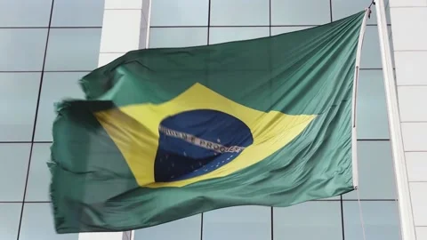 Brazilian flag blowing in a storm wind with corporate building in the background Stock Footage 131277564