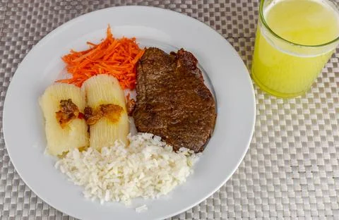 Brazilian food dish with steak and rice and carrot and cassava with eye Stock Photos