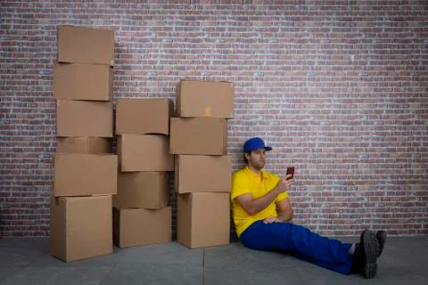 Brazilian mailman using a smartphone in front of a lot of packages in a depos Stock Photos