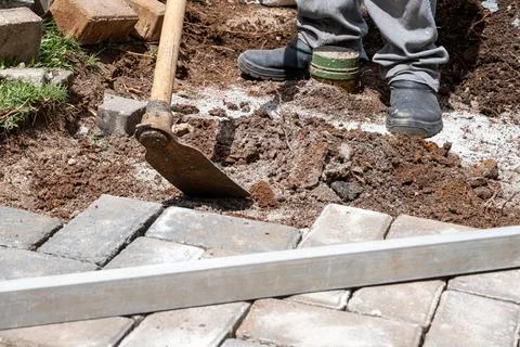 Brazilian using a hoe to prepare the soil for laying concrete blocks. Stock Photos