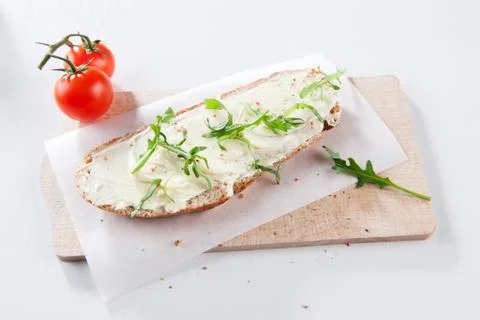 Bread and butter with rocket on a board Stock Photos