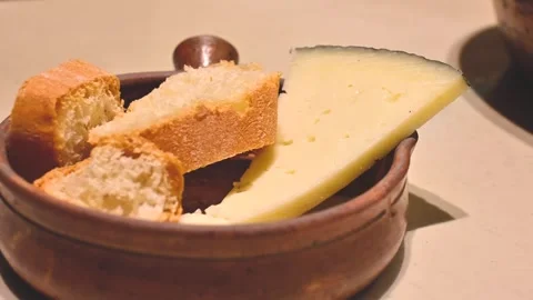 Bread and cheese on rustic plate under warm light 4K Stock Footage 319527928