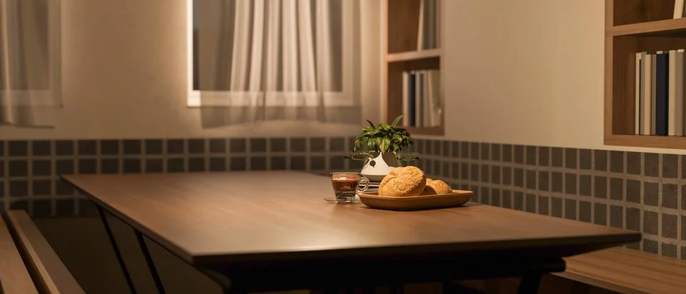 Bread and coffee cup aside pot plant on wooden table aside window and books.. Stock Illustration
