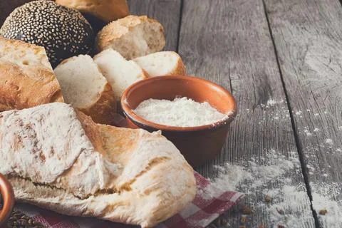 Bread and flour on rustic wooden table with bowl of flour Stock Photos