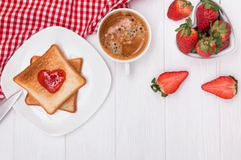 Bread and jam in heart shape, strawberries and coffee on the white table Stock Photos