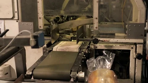 Bread and rolls being packed in plastic bags by machine in a bakery factory Stock Footage 217944920