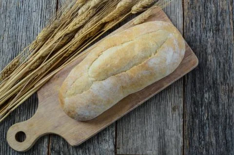 Bread and wheat on a rustic cutting board Foto stock